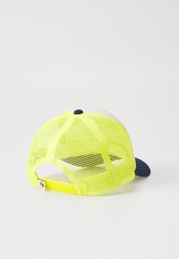 Sárga hálós baseball sapka sötétkék csúccsal és állítható pánttal; a tetején kerek gomb, hátul pedig logós címke található.