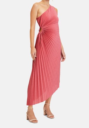 Robe plissée rose asymétrique avec un nœud sur le côté et une texture métallique, accompagnée de sandales à talon bloc de couleur claire.