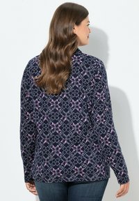 Marinblå långärmad topp med ett geometriskt blommönster i rosa och vitt. Mjuk tyg, figurnära design med rund hals och sidoklipp.