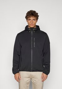 Svart lett jakke med glidelås foran, justerbar hette og neongule detaljer. Designet med et minimalistisk stil og glatt tekstur.