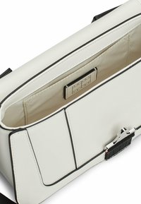 Bolso de cuero sintético blanco con detalles en negro, forma rectangular, correa ajustable, con cierre de cremallera y etiqueta interior de marca.