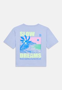 Ανοιχτό μπλε βαμβακερό T-shirt με γραφιστικό σχέδιο που απεικονίζει φοίνικες, ένα ηλιοβασίλεμα και το κείμενο «SLOW DREAMS» με έντονα νέον πράσινα και ροζ γράμματα.