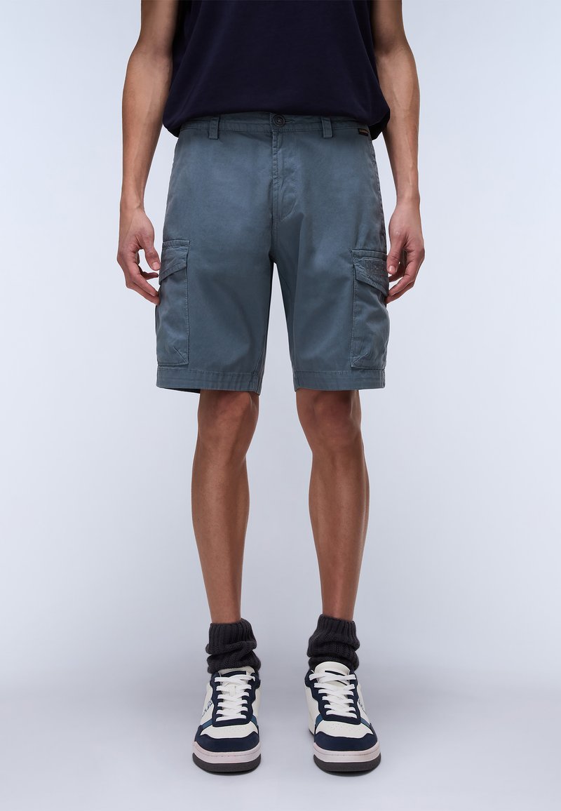 Cargo shorts in slate gray, featuring side pockets, a button closure, and a soft, textured fabric. Paired with high-top sneakers.