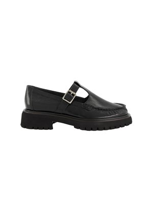 Black leather Mary Jane shoe with adjustable buckle strap, chunky lug sole, and moc toe stitching.