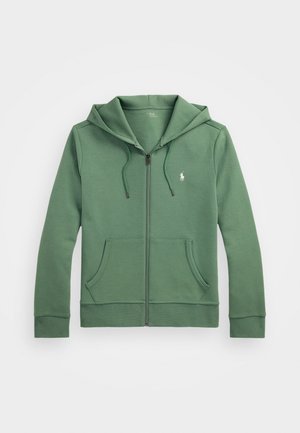 Sweatshirt verde com fecho éclair, feito de um tecido suave, apresentando uma grande capuz, dois bolsos frontais e um pequeno logótipo bordado no peito.