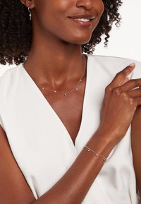 Zilveren juwelenset met een delicate kettinghalsband met kleine ronde hangers en een bijpassende armband met een vergelijkbaar ontwerp.