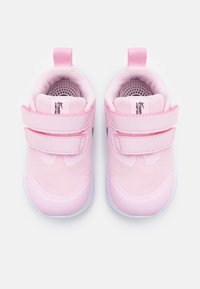 Zapatillas de tela rosa con malla y superposiciones sintéticas, que presentan dos correas de velcro, un interior acolchado y suelas de goma blanca.