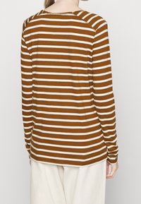 Brown and cream striped long-sleeve shirt with a rounded neckline, a relaxed fit, and visible stitching along the edges.