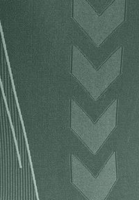 Tissu vert texturé avec un motif de quatre chevrons pointant vers le bas en rangée verticale et des lignes courbes sur le côté gauche.