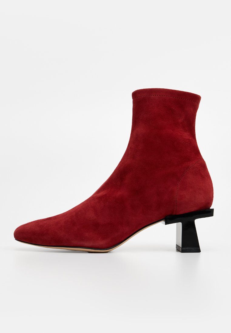 Czerwone zamszowe botki za kostkę z wężowym noskiem i blokowym obcasem. Gładka tekstura i minimalistyczny design. Zaokrąglone górne krawędzie.