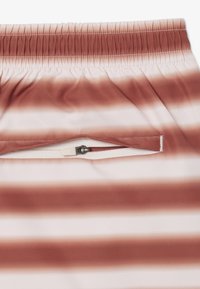 Pantalones cortos ligeros con una amplia cinturilla elástica, que presentan un patrón de franjas en degradado horizontal en marrón y blanco, y un bolsillo con cremallera.
