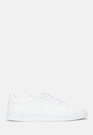 Hvite lær sneakers med en glatt tekstur, som har flate lisser, rund tå og en subtil logo på siden. Tykk hvit såle.
