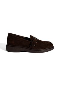 Mocassin en daim brun foncé avec bride à boucle noire et semelle en caoutchouc texturée, présenté de profil sur fond blanc.