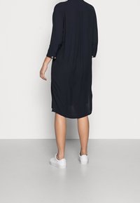 Abito camicia blu navy realizzato in tessuto leggero, con maniche a tre quarti, un dettaglio a bottoni ai polsini e un orlo curvo.