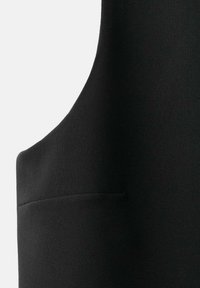 Gilet in tessuto nero con una texture liscia, caratterizzato da un collo curvo e da una tasca laterale discreta, che sottolinea un design su misura.
