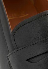 Svarta läderloafers med en texturerad yta, stickade detaljer och en utskärning nära den övre kanten. Slät innerfoder.