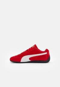 Baskets rouges Puma avec bande blanche latérale et semelle noire, vues de côté extérieur sur fond blanc.