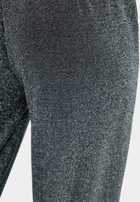 Ciemnoszare dżinsy o delikatnym połysku, z fakturowaną powierzchnią i prostym krojem. Brak widocznych elementów metalowych lub wzorów.