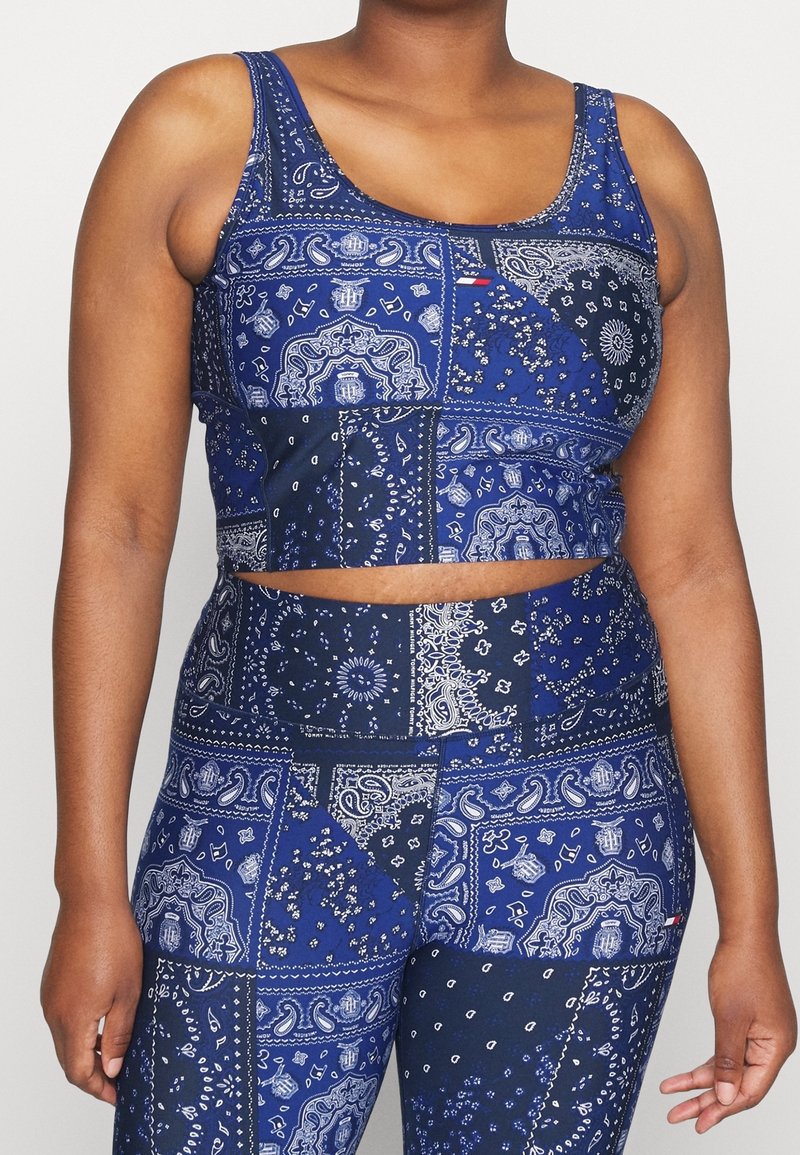 Torso of a person wearing a blue patchwork bandana-print crop top and matching high-waisted leggings.