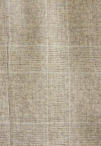 Nahaufnahme eines beige-weißen gewebten Stoffs mit einem dezenten Gittermuster und sichtbarer Struktur verflochtener Fäden.