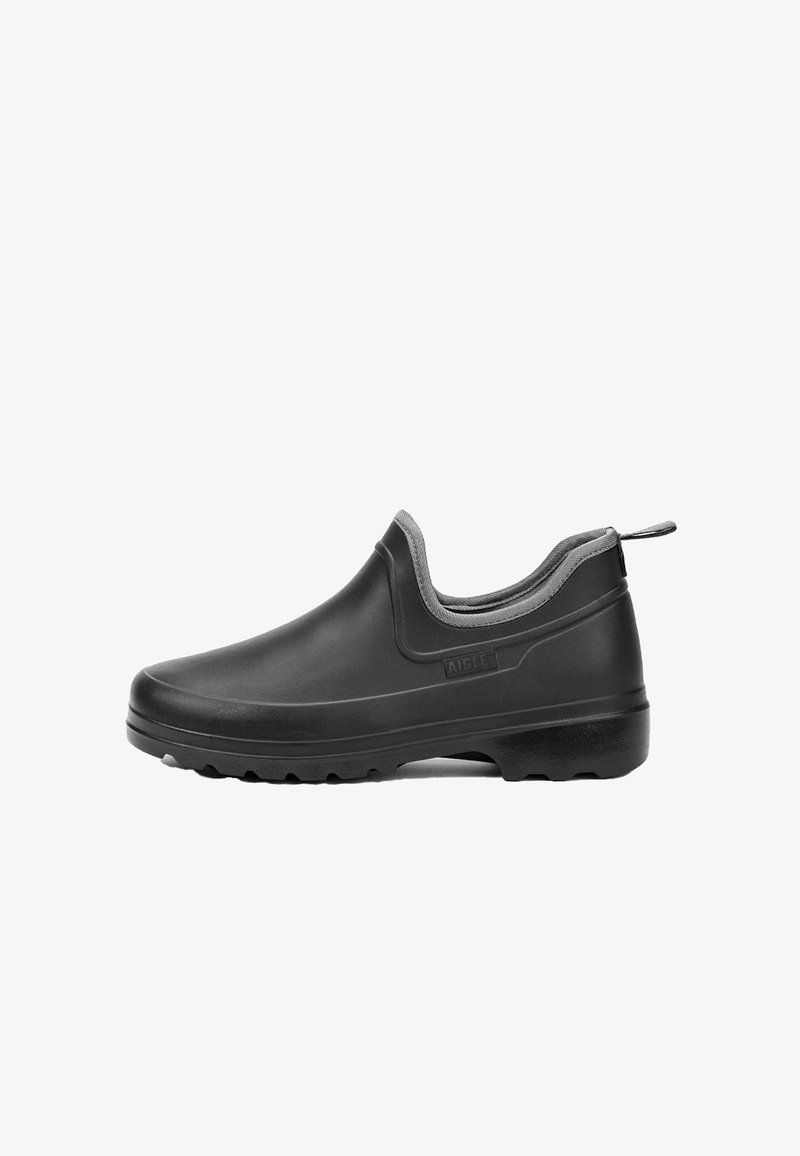 Black rubber slip-on shoe with a low profile, textured upper, grey accent around the collar, and a pronounced treaded sole for traction.