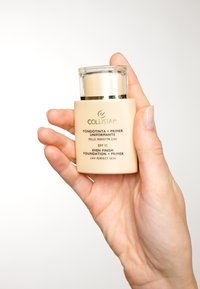Collistar Even Finish Foundation + Primer-flaska, beige med en genomskinlig kork och guldaccenter, hålls i en hand, med präglad text.