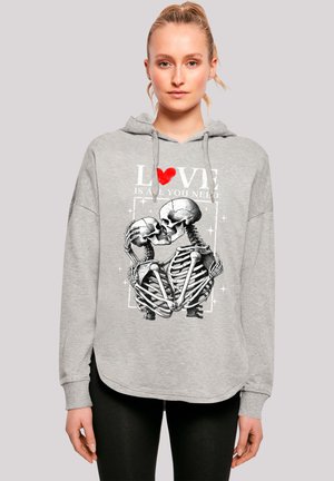 Graue Kapuzenjacke mit lässigem Schnitt, ausgestattet mit einem grafischen Motiv von küsstenden Skeletten und dem Text "LIEBE IST ALLES, WAS DU BRAUCHST" in Rot und Weiß.