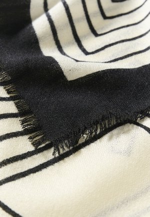 Schwarz- und cremefarbenes gewebtes Textil mit geometrischen Formen, das einen ausgefransten Rand und eine weiche Textur aufweist. Das Design enthält kräftige, lineare Muster.