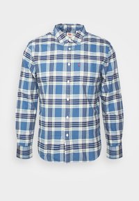 Chemise à manches longues pour hommes à carreaux bleu, blanc et vert avec fermeture à boutons sur le devant et poche poitrine avec une petite étiquette rouge.