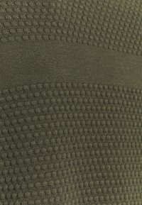Gros plan sur un tissu vert olive avec des rayures horizontales alternant entre un tricot lisse et texturé.