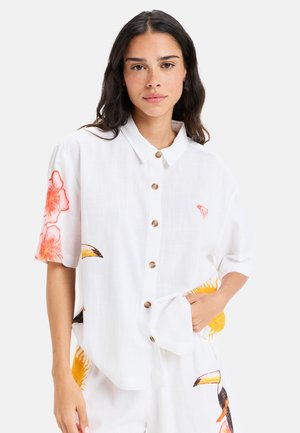 Camisa blanca de botones con mangas cortas, que presenta acentos florales naranjas y un pequeño logo. Fabricada en un tejido ligero similar al lino.