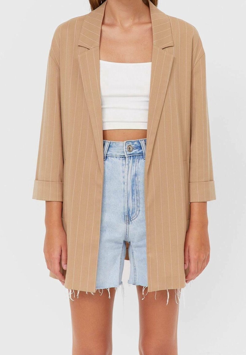 Blazer beige à fines rayures avec manches 3/4 sur top court blanc et short en jean bleu clair taille haute avec ourlet effiloché.