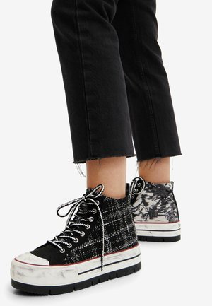 Sneaker alte a scacchi in bianco e nero con tessuto testurizzato, punta bianca e suola nera spessa; abbinate a jeans neri a vita alta.