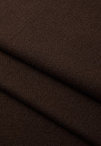Tissu marron foncé avec une texture douce, montrant des couches soigneusement pliées, mettant en valeur sa douceur et sa couleur riche.