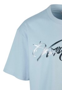 Šviesiai mėlyna trumpa rankovė marškinėlių su minkšta medžiaga, su sidabro metaline grafika, stilizuotu šriftu ir žvaigždžių akcentais.