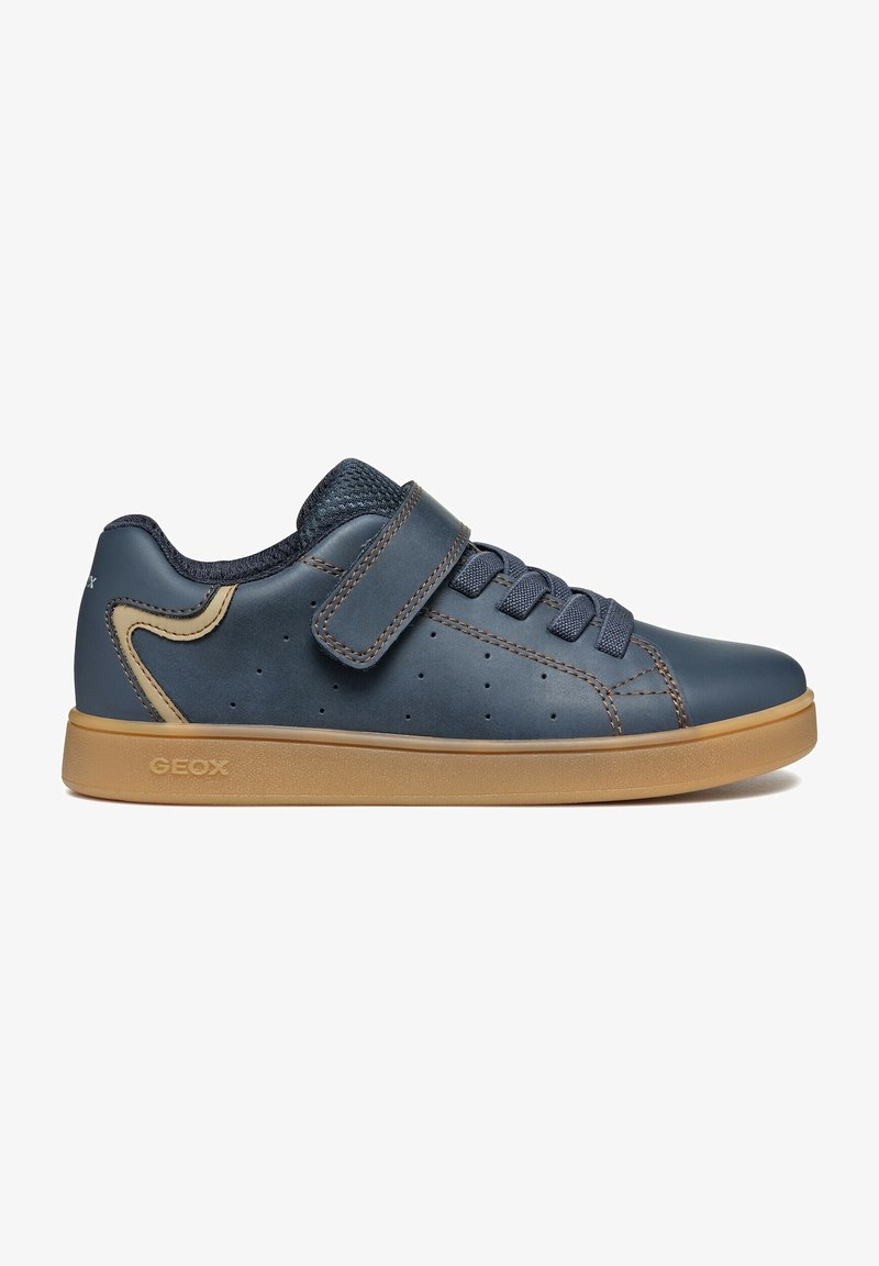 Baskets basses bleu marine avec semelle beige, fermeture velcro, lacets et accent beige au talon, conçues pour un usage décontracté.