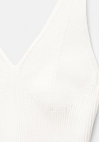 Fehér bordázott bralette, mély V-nyakkivágással, texturált anyaggal és réteges varrással a szélek mentén az extra részletekért.
