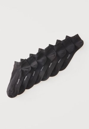 Sept paires de chaussettes noires basses disposées en rang sur un fond blanc avec un petit texte blanc sur chaque paire.