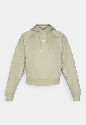 Lys grøn cropped hoodie med gule syninger, kengurulomme og et lille hvidt logo på brystet. Blød lærredstekstur.