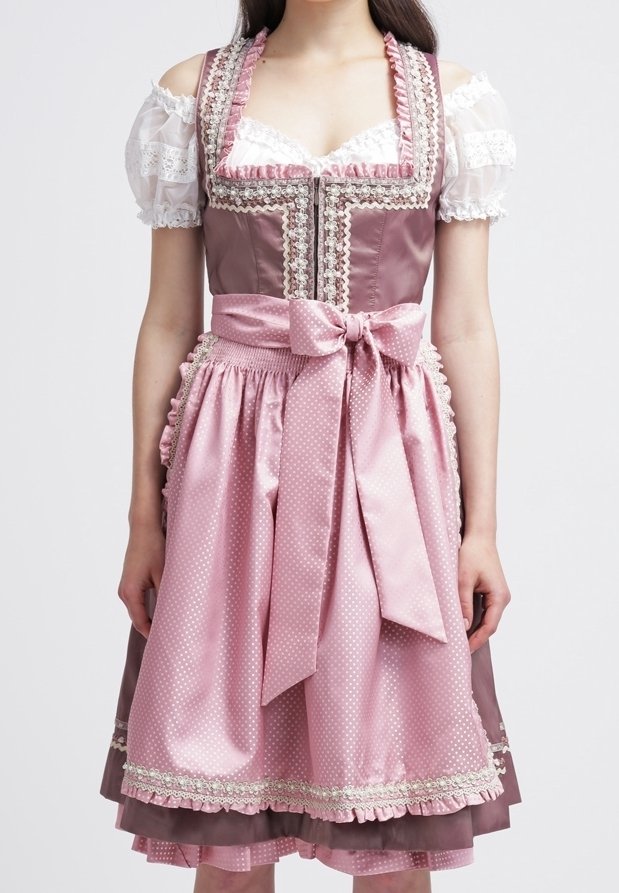 Femme portant une robe traditionnelle dirndl rose et mauve avec un corsage orné de dentelle, des manches bouffantes en dentelle et un grand nœud attaché au tablier à la taille.