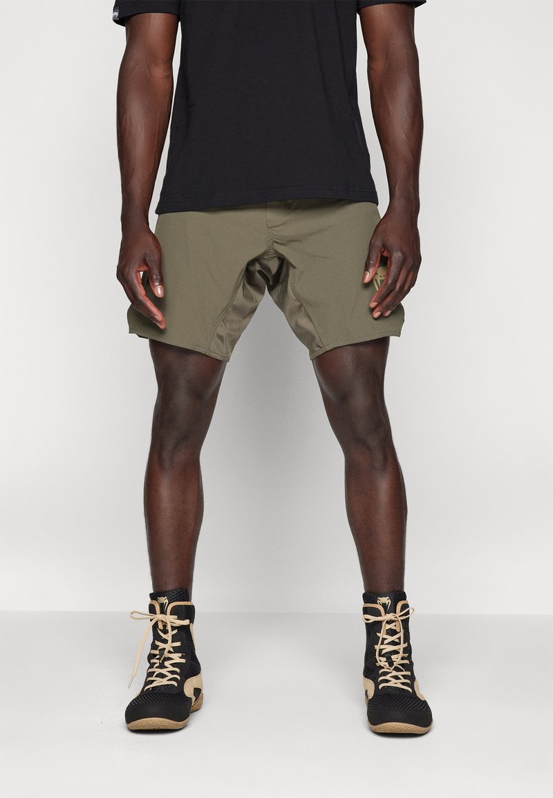 Olive green shorts with a lightweight design, featuring a mid-thigh cut and a side pocket. Worn with black high-top mesh shoes.