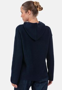 Sweat à capuche bleu marine foncé avec une texture douce, manches longues et poche kangourou. Présente une coupe décontractée avec ourlet et poignets côtelés.