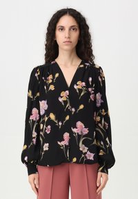 Blusa nera con stampa floreale in rosa, giallo e viola. Presenta un colletto a V, maniche a sbuffo e una vestibilità comoda. Realizzata in tessuto leggero.
