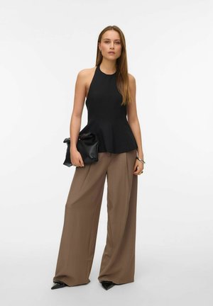 Melna bez piedurknēm pepluma blūze saskaņota ar augsto jostasvietu, platām brūnām biksēm. Aksesuāri ietver melnu kluču un smailus zābakus.