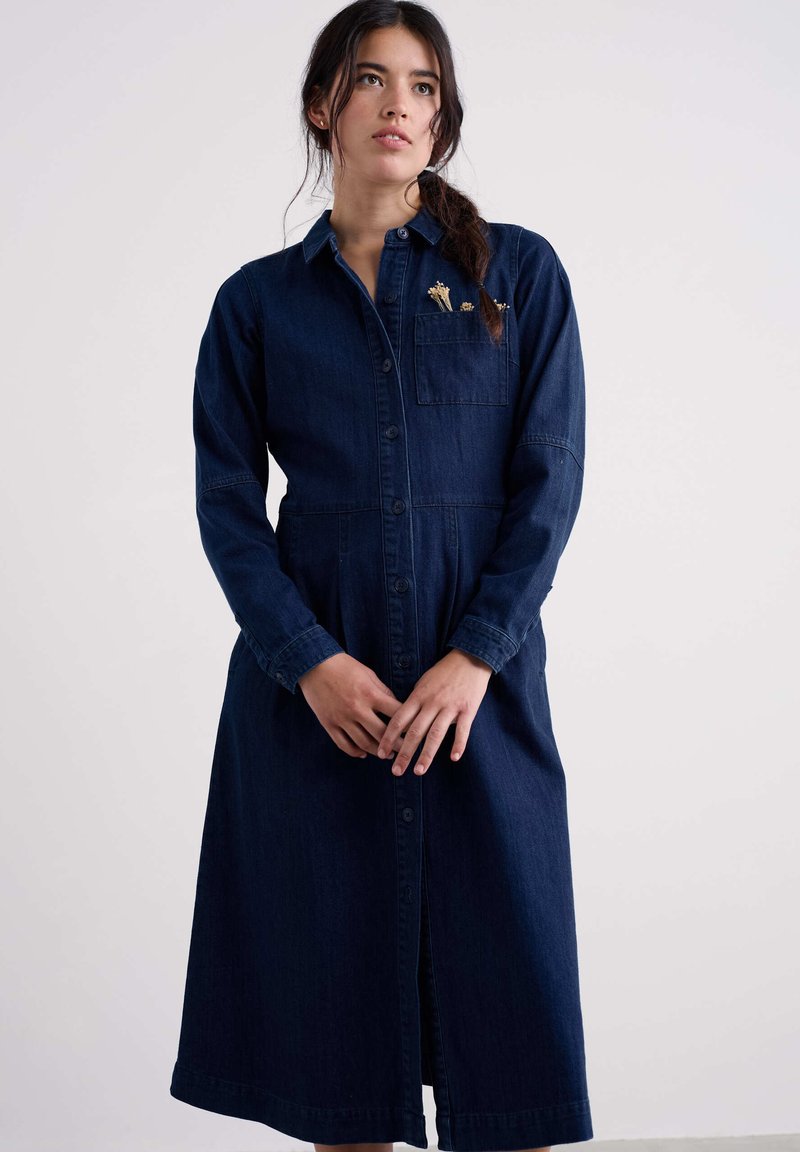 Denimjurk in donkerblauw met lange mouwen, kraag, knopen aan de voorkant, getailleerde taille en een zak met subtiele bloemrijke borduurdetails.
