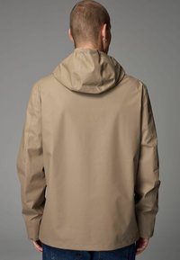 Beige wasserdichte Jacke mit Kapuze, featuring eine glatte Textur, lange Ärmel und einen lockeren Schnitt. Sichtbare Nähte und minimalistische Designdetails.