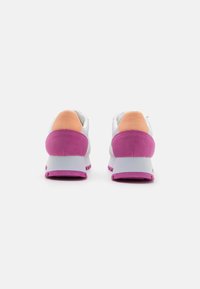 Hvite joggesko med rosa og oransje detaljer, avrundet form, teksturert bakside og tykke gummisåler. Lett design med snøring.