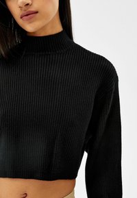 Svart ribbad stickad kort tröja med hög hals och långa ärmar, med en texturerad tyg och en slät finish.