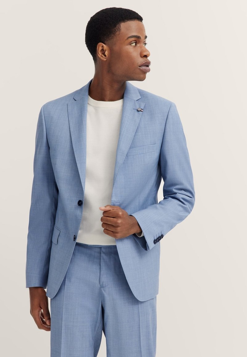 Helles blaues, maßgeschneidertes Anzug aus strukturiertem Stoff, mit Reverskragen, einer Knopfleiste und einer Brusttasche. Trägt man über einem weißen Hemd.