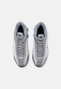 Graue und weiße Sportschuhe mit einem strukturierten Design, bestehend aus Mesh- und synthetischen Materialien, Schnürsenkeln und einem schwarzen Innenraum. Blaue Akzente sind vorhanden.